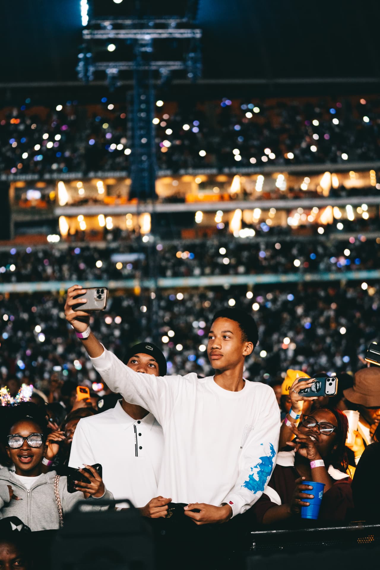 Fan taking a selfie with the lit-up stadium crowd behind
