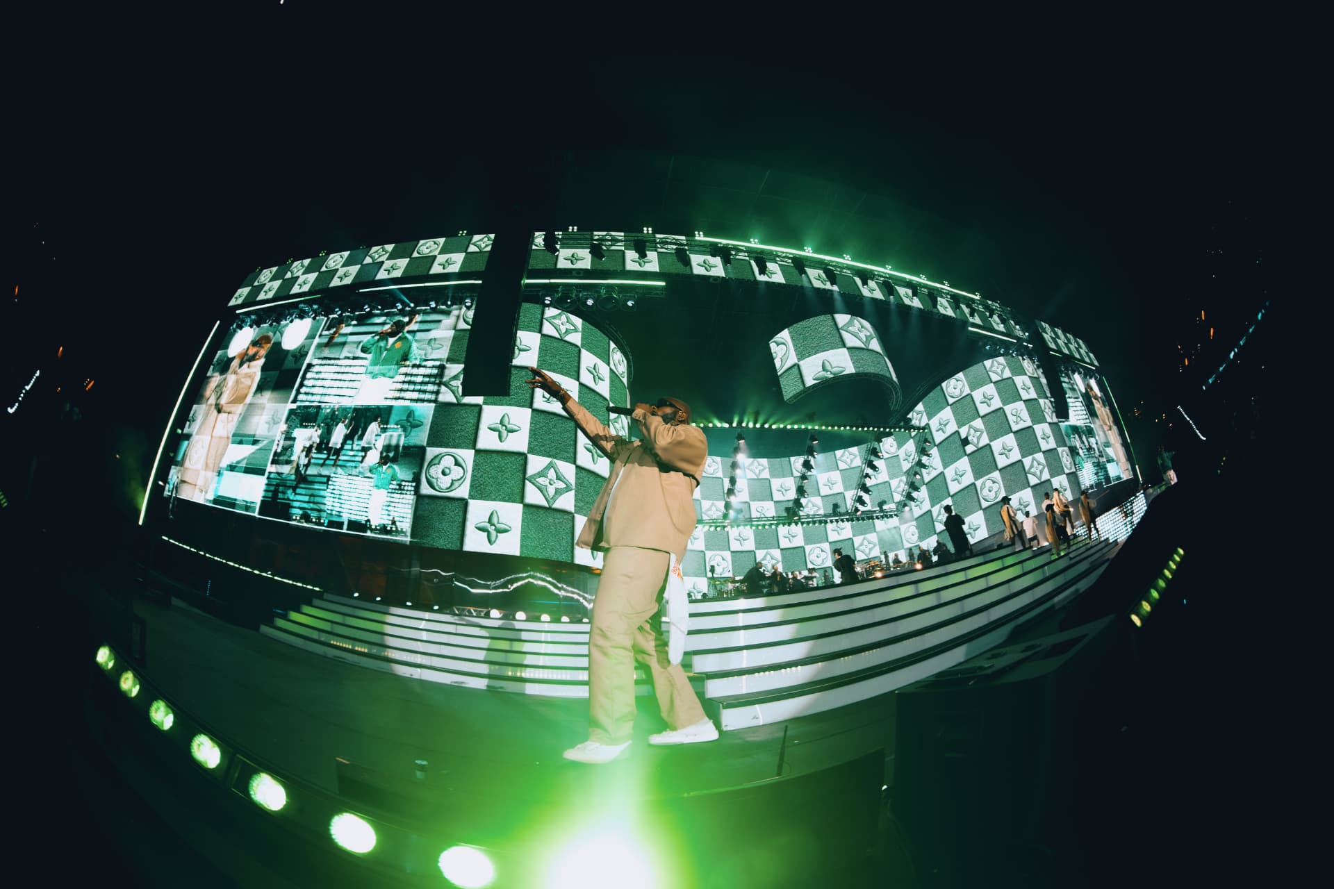 Performer on stage in front of green checkered screens
