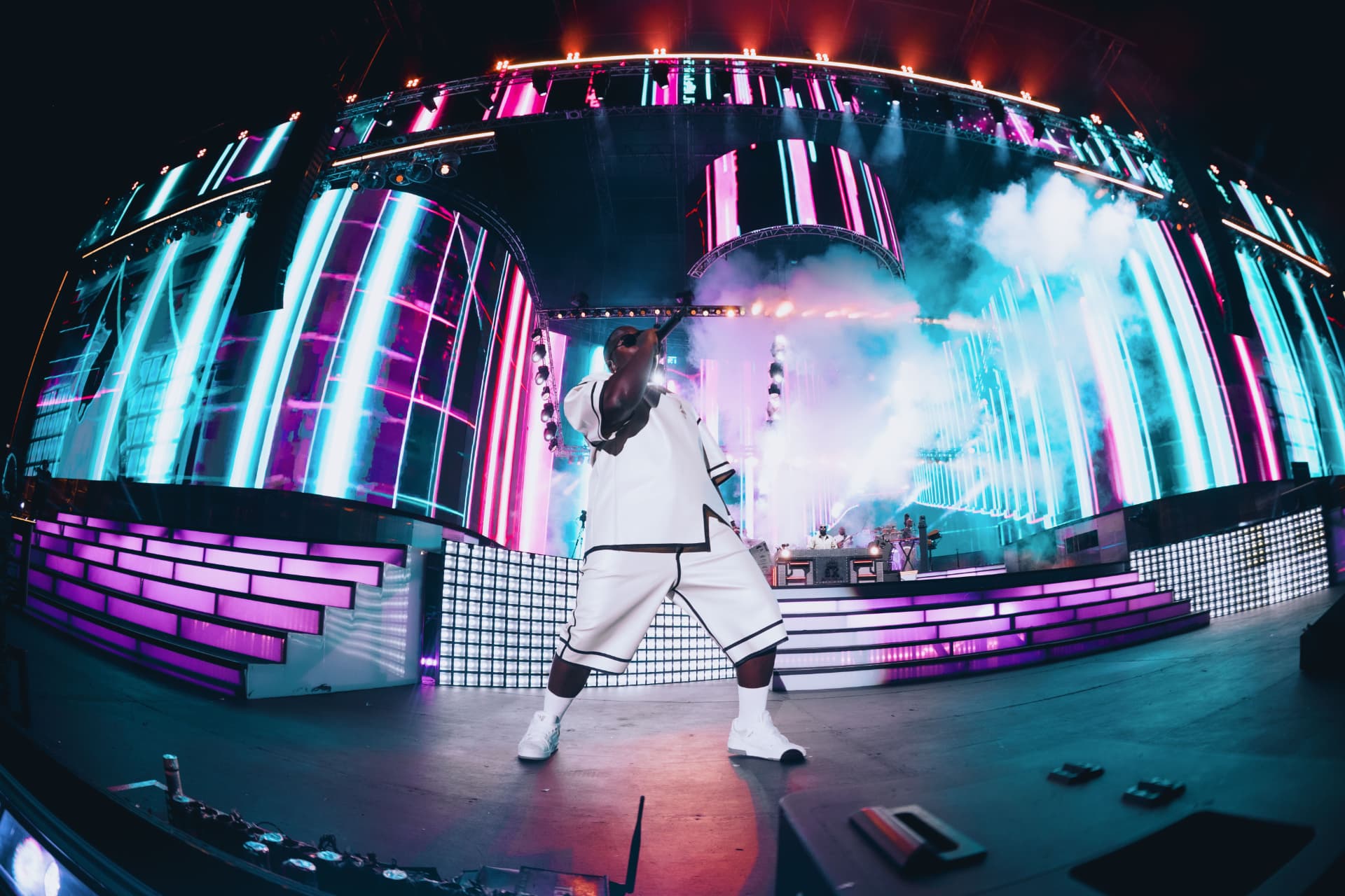 Performer in white on stage with smoke and neon columns
