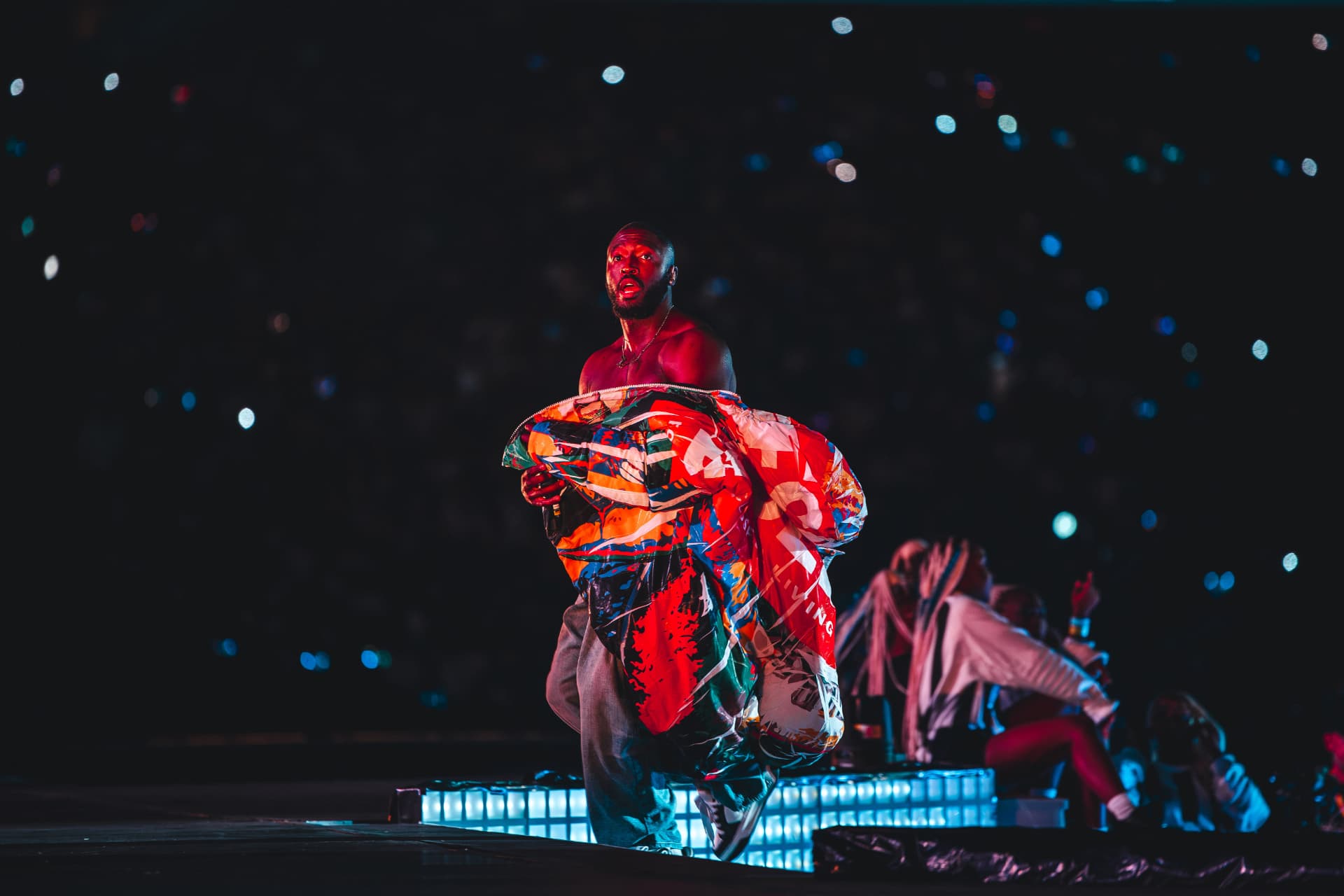 Performer carrying a colourful puffer jacket across the stage
