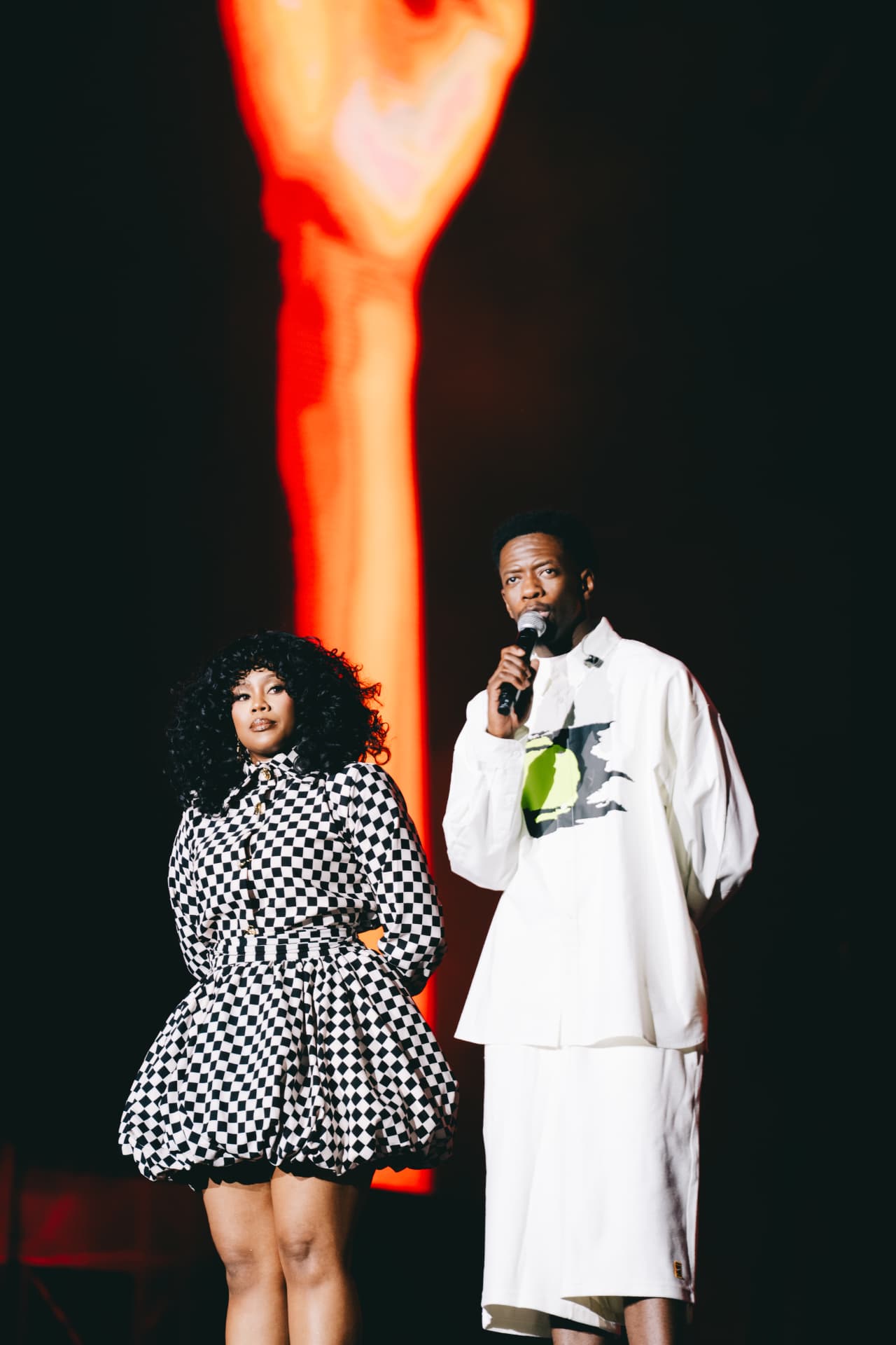 Hosts on stage in front of a flame-lit raised fist screen