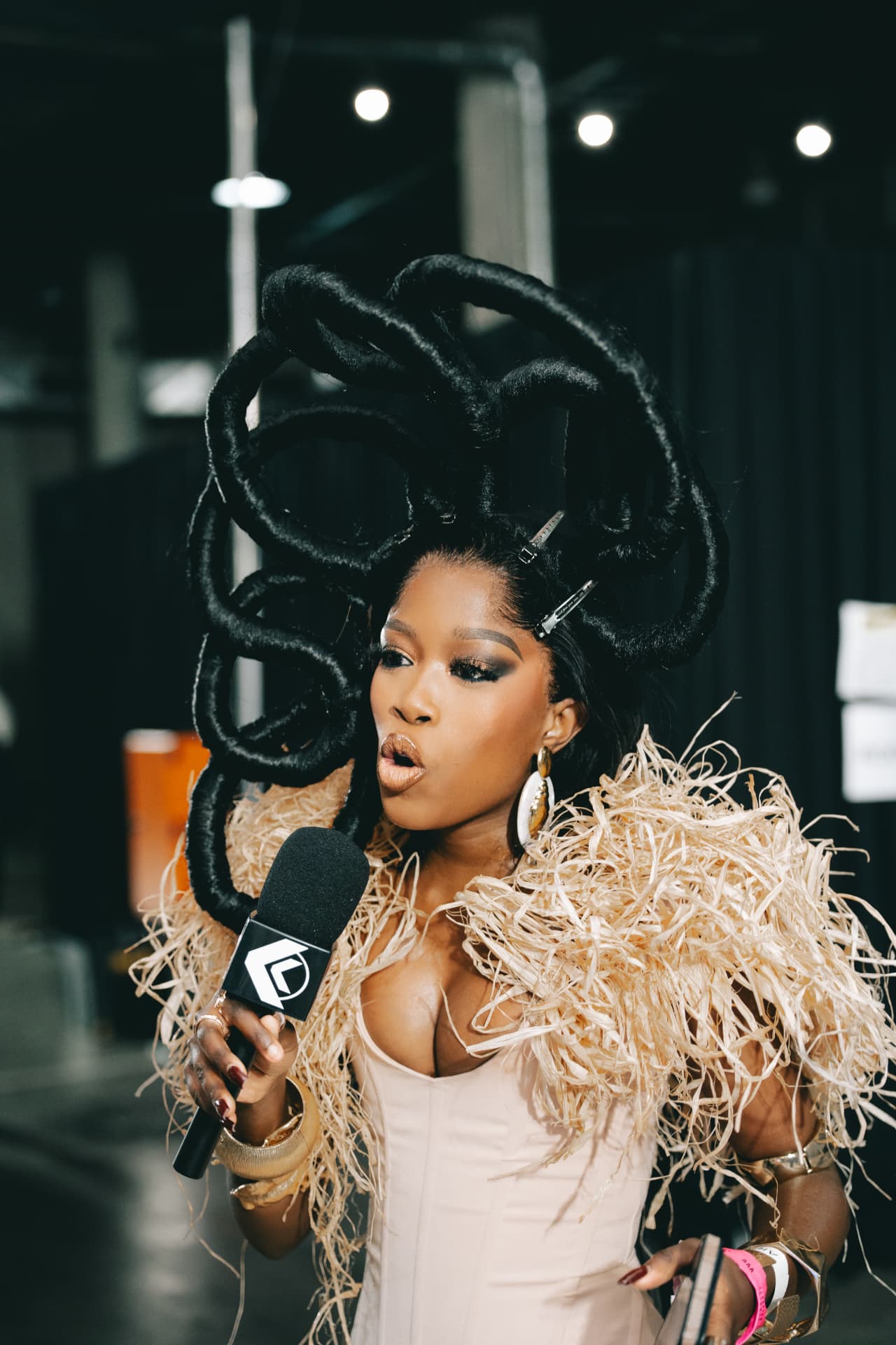 Media personality with sculpted hair interviewed backstage