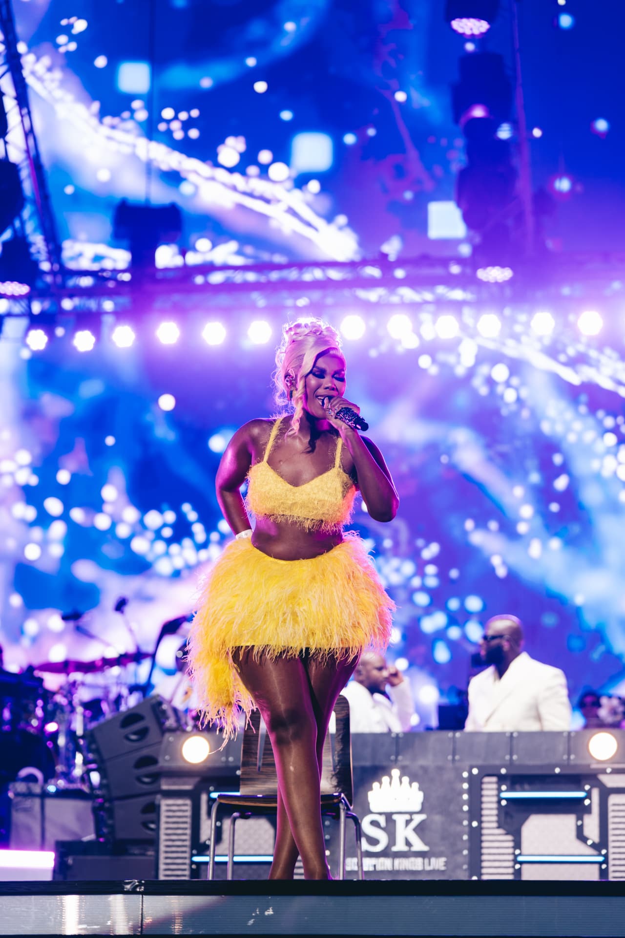 Vocalist in yellow feathers performing in front of the SK stage