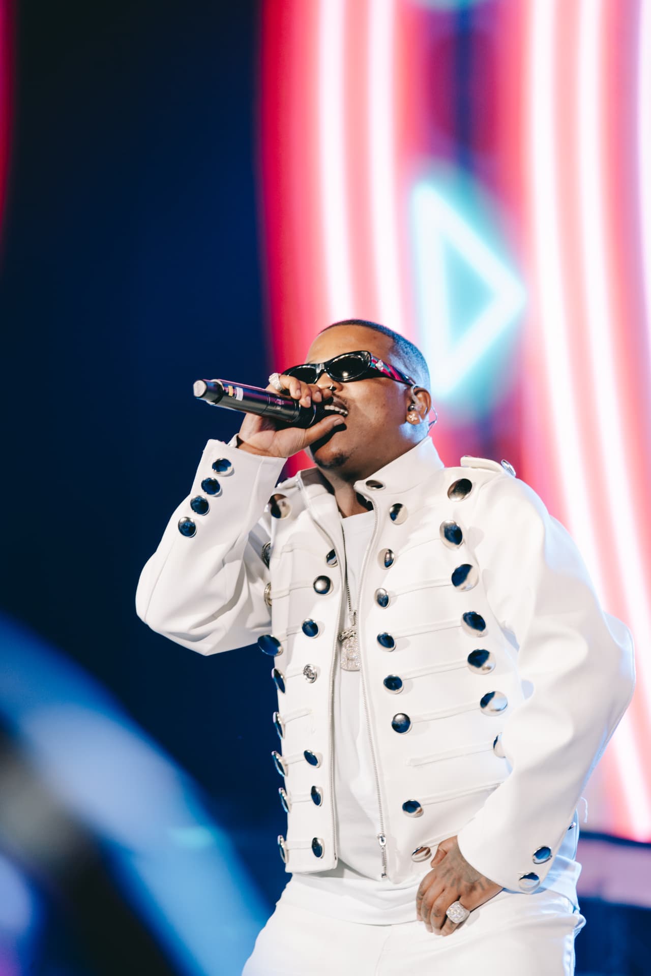 Performer in a studded white jacket singing into the mic