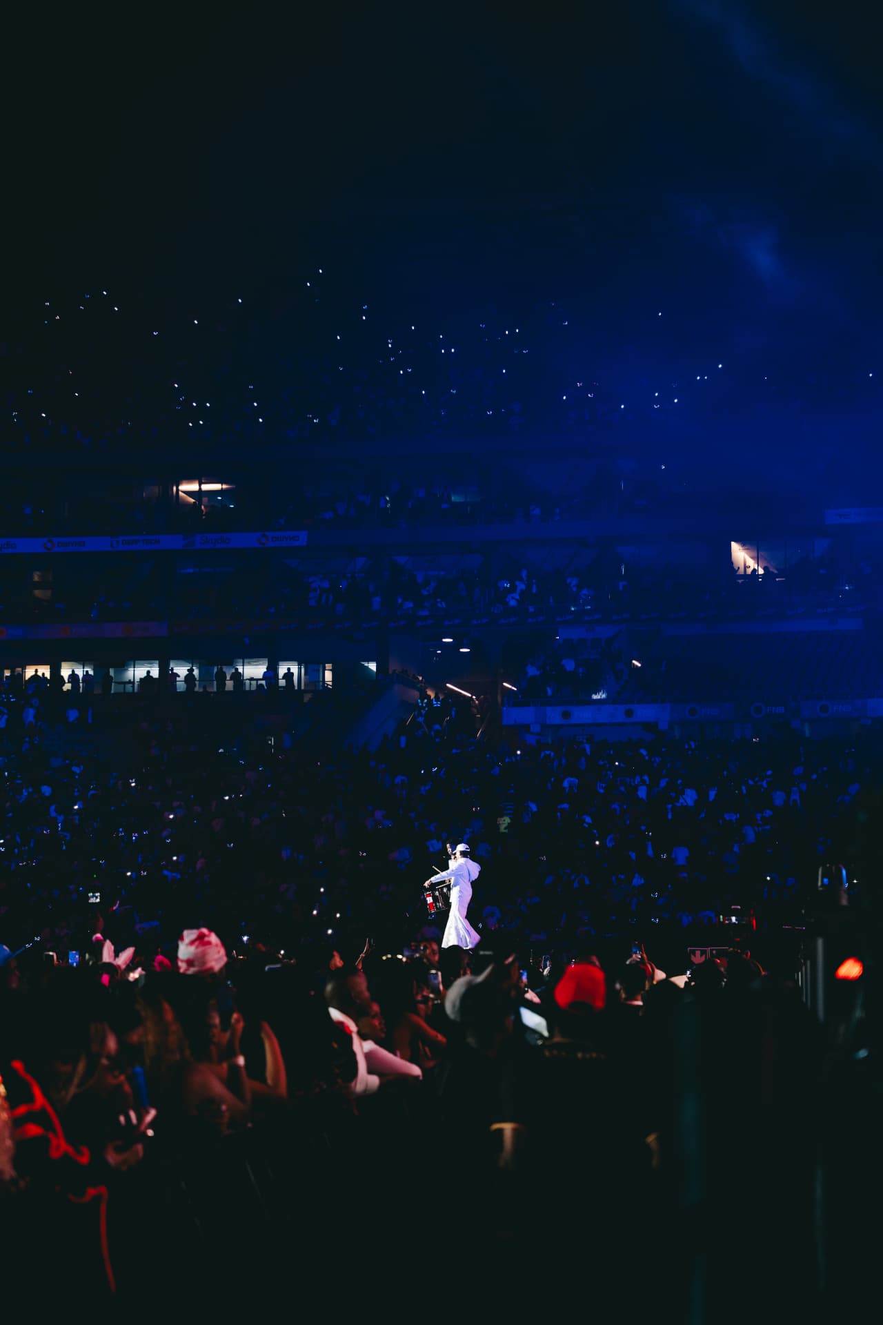 Drummer in white surrounded by a sea of phone lights