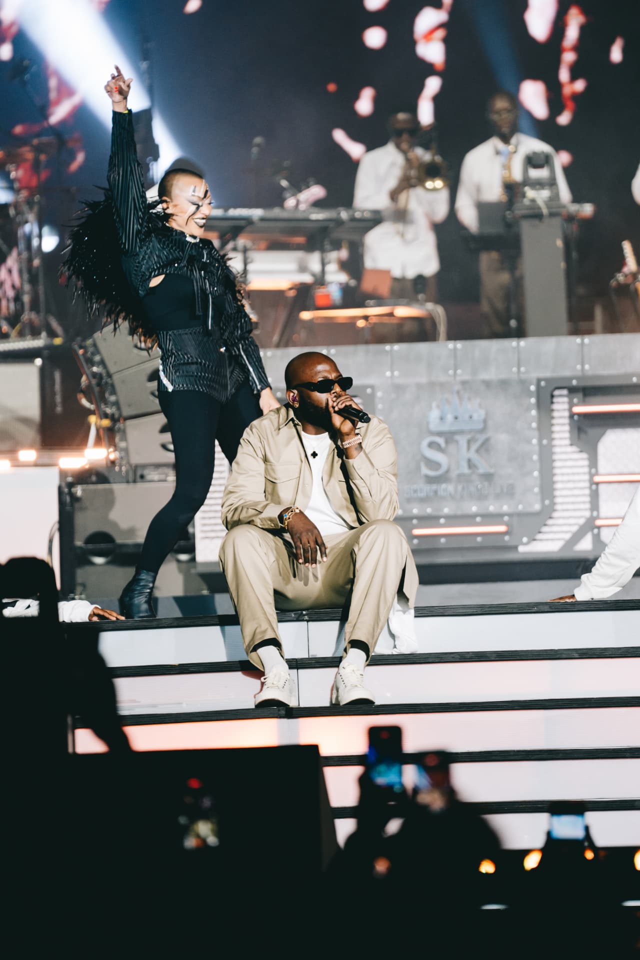 Scorpion King performing seated on the stage steps with a dancer behind