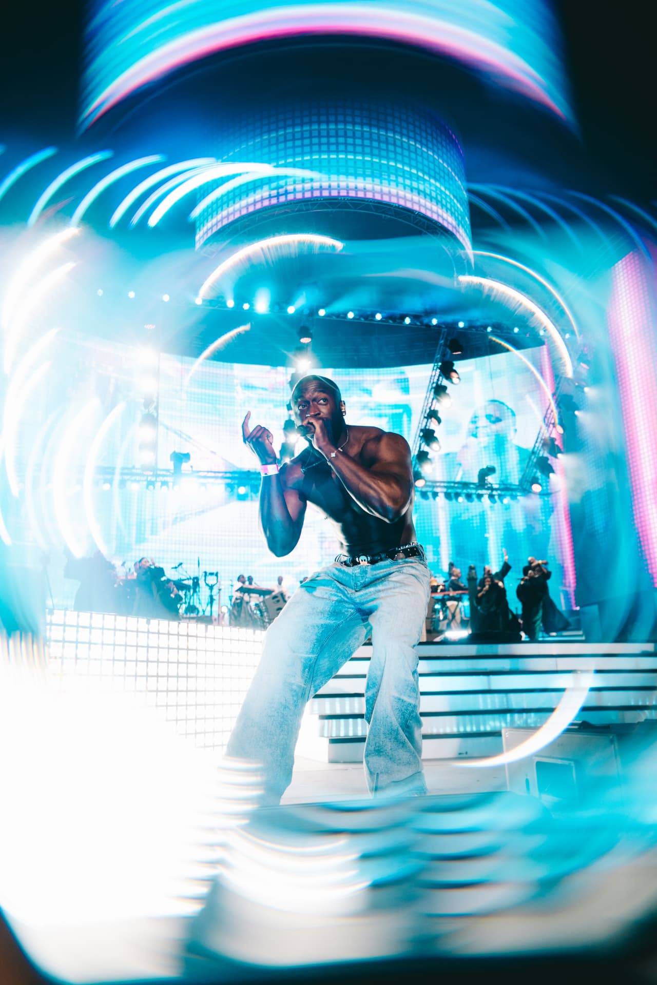 Performer on stage framed by swirling blue light trails