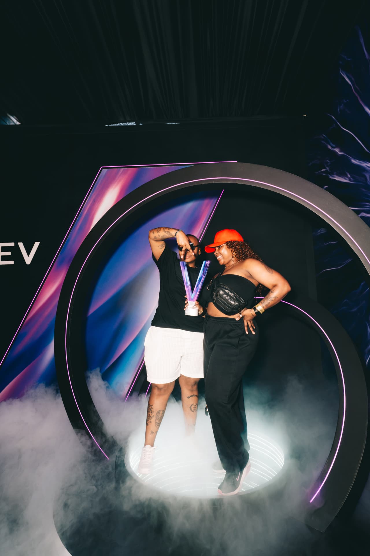 Guests posing with a trophy inside the illuminated VEEV installation