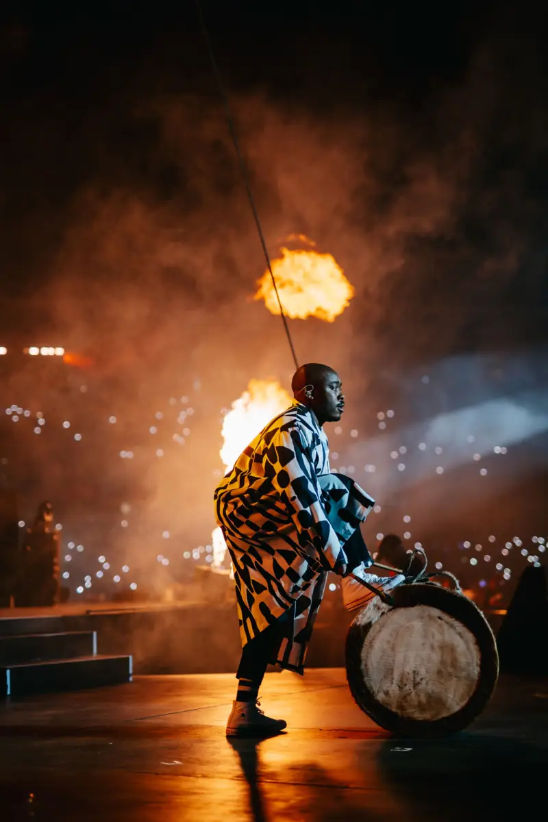 Traditional drummer on stage framed by flames